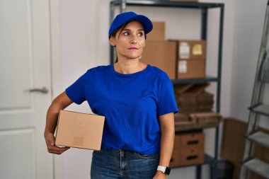 Middle age brunette woman working wearing delivery uniform and cap looking sleepy and tired, exhausted for fatigue and hangover, lazy eyes in the morning. 