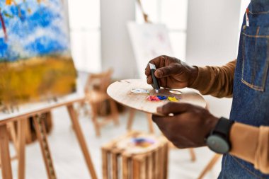 Palet sanat stüdyosunun rengini karıştıran Afrikalı Amerikalı sanatçı..