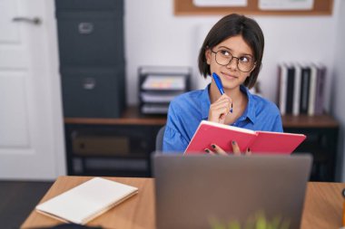 Ofiste dizüstü bilgisayar kullanan sevimli İspanyol iş kadını.