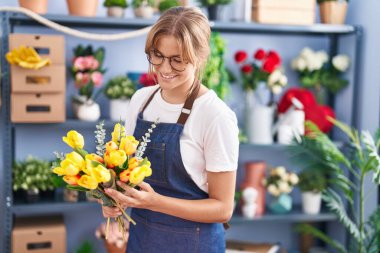 Young blonde girl florist make bouquet of flowers at florist