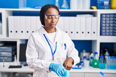 Bilim adamı üniforması ve eldiven laboratuarı giyen Afrikalı Amerikalı kadın.