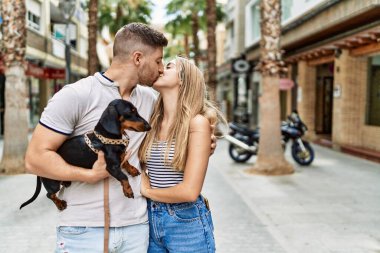 Genç beyaz bir çift şehirde köpekle mutlu bir şekilde duruyor..