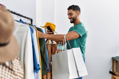 Genç Arap müşteri elbise mağazasından kıyafet alışverişine resim yapıyor.