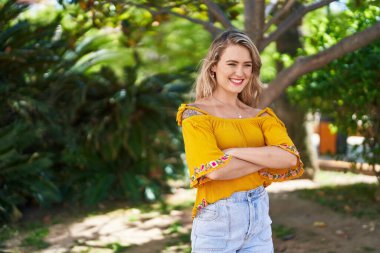 Young woman smiling confident standing with arms crossed gesture at park