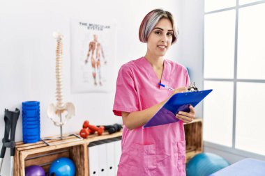 Genç beyaz fizyoterapist klinikteki panoda mutlu bir yazı yazıyor..