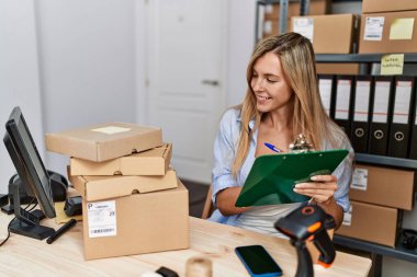 Genç sarışın kadın ecommerce iş işçisi ofisteki panoya yazıyor.