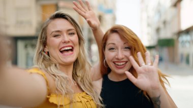 İki kadın sokakta video görüşmesi yaparken kendine güveniyor.