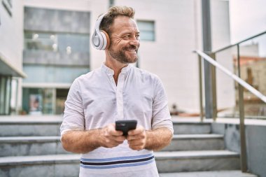 Şehirde akıllı telefon kullanan orta yaşlı bir adam.