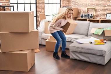 Yeni evinde sırt ağrısı çeken genç bir kadın.