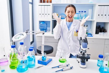 Bilim adamlarının laboratuvarında çalışan genç esmer kadın başarının çılgınlığını kollarını kaldırarak ve gözlerini kapatarak heyecanla haykırarak kutluyor. Kazanan konsept 