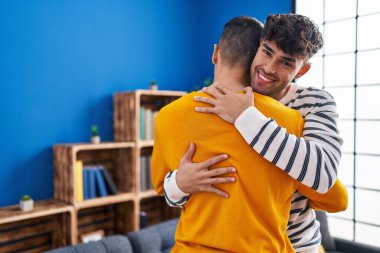 İki erkek, evde birbirlerine sarılıyorlar.