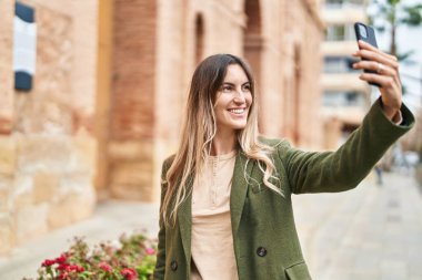 Young woman smiling confident making selfie by the smartphone at street
