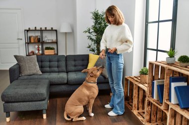 Genç, beyaz bir kadın köpeğini evde besliyor.