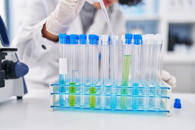 Genç Ortadoğulu bilim kadını laboratuardaki test tüplerine sıvı döküyor.