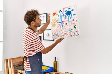 Sanat stüdyosunun duvarına tuval asan genç bir İspanyol.