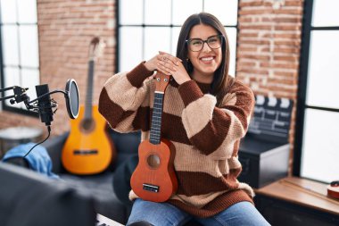 Genç İspanyol kadın müzisyen müzik stüdyosunda ukulele tutuyor.