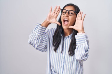 Young hispanic woman wearing glasses smiling cheerful playing peek a boo with hands showing face. surprised and exited 