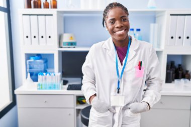 African american woman wearing scientist uniform standing at laboratory