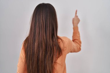 Genç esmer kadın beyaz arka planda dikiliyordu. Geriye doğru poz veriyordu. 