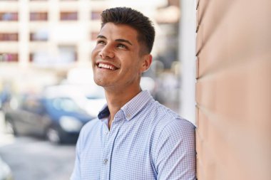 Young hispanic man smiling confident looking to the side at street