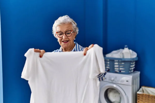 Starší Šedovlasá Žena Usmívá Sebevědomě Drží Bílé Tričko Prádelně — Stock fotografie