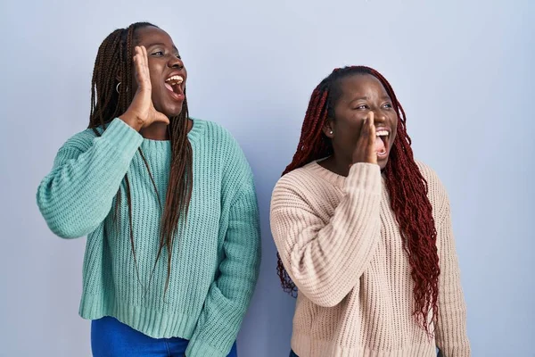 青い背景の叫びの上に立っている2人のアフリカ人女性と口の上に手で大声で叫んでいる コミュニケーションの概念 — ストック写真