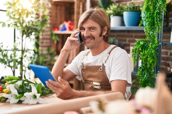 Ung Blond Man Florist Talar Smartphone Med Pekplatta Blomsteraffär — Stockfoto