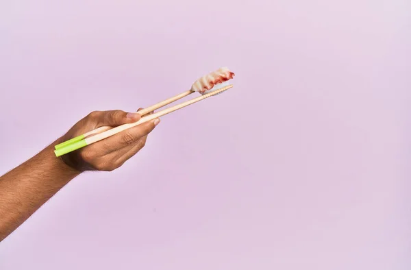 孤立したピンクの背景に箸でタコの握りを持つ男の手 — ストック写真