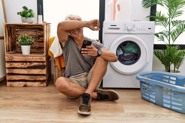 Junger Blonder Mann Wäscht Mit Smartphone Lächelt Fröhlich Und Guckt — Stockfoto