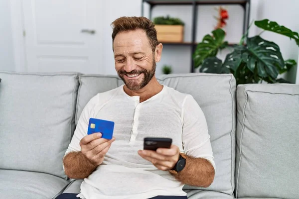 Middelbare Leeftijd Spaanse Man Met Behulp Van Smartphone Creditcard Thuis — Stockfoto