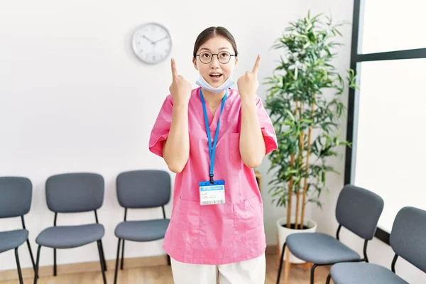 Young Asian Nurse Woman Medical Waiting Room Amazed Surprised Looking — Stock Photo, Image