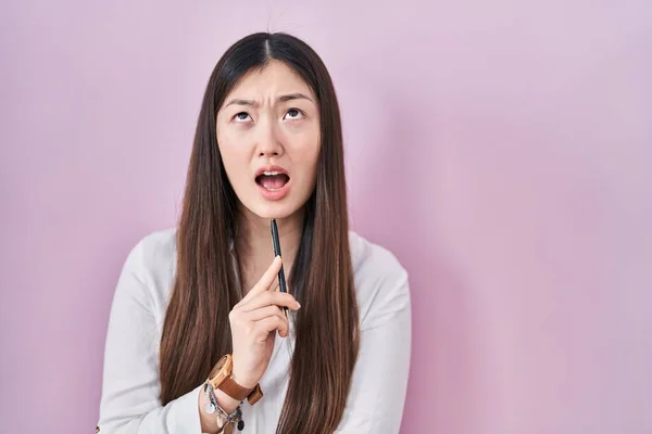 中国の若い女性を保持鉛筆上ピンクの背景怒っていると怒っている叫び不満と激怒 怒りで叫んで検索アップ — ストック写真