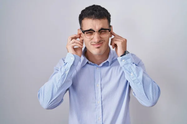 ビジネス用の服を着たハンサムなヒスパニック系の男性と 大きな音楽のノイズのためにいらいらする表情で指で耳を覆う眼鏡 聴覚障害の概念 — ストック写真