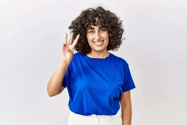 年轻的中东女人站在孤立的背景下 用第三根手指指指指点点 自信而快乐地微笑着 — 图库照片