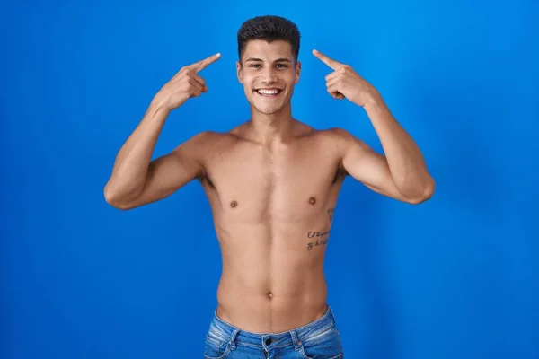 Joven Hombre Hispano Pie Sin Camisa Sobre Fondo Azul Sonriendo —  Fotos de Stock