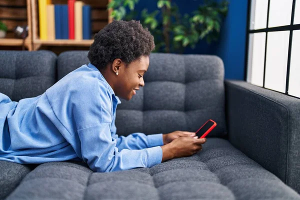 Mujer Afroamericana Usando Teléfono Inteligente Tumbado Sofá Casa —  Fotos de Stock