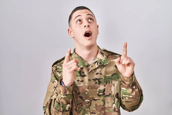 Jovem Vestindo Uniforme Exército Camuflagem Surpreso Surpreso Olhando Para Cima — Fotografia de Stock