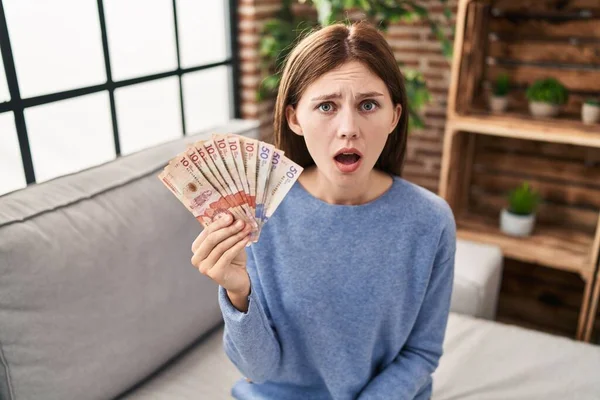 Young Brunette Woman Holding Colombian Pesos Scared Amazed Open Mouth — Stock Photo, Image