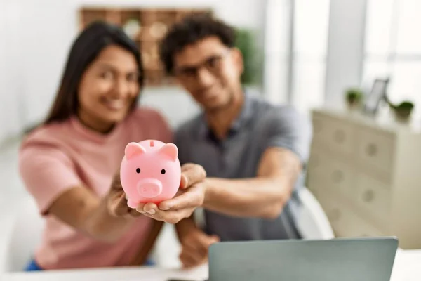 Young Latin Couple Smiling Happy Holding Piggy Bank Sitting Table — Φωτογραφία Αρχείου