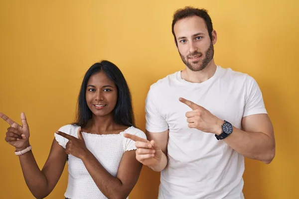 Interracial Couple Standing Yellow Background Smiling Looking Camera Pointing Two — Foto Stock