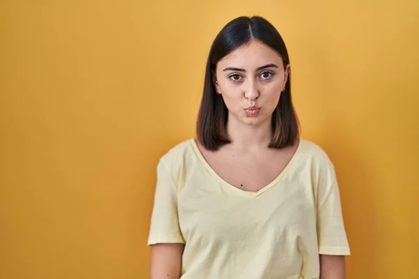 Hispanic Girl Wearing Casual Shirt Yellow Background Puffing Cheeks Funny — Zdjęcie stockowe