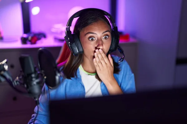 Young Hispanic Woman Wearing Headphones Playing Video Games Covering Mouth — Stock Photo, Image