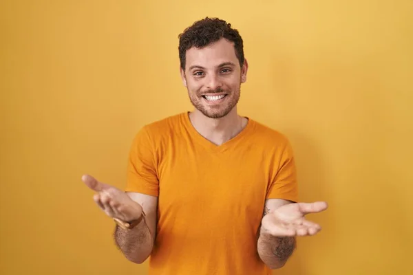 Young Hispanic Man Standing Yellow Background Smiling Cheerful Offering Hands — Stock Photo, Image