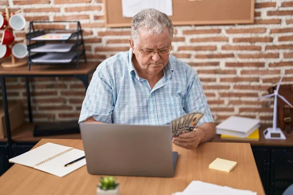 中年白发苍苍的生意人在办公室用笔记本电脑数钱 — 图库照片