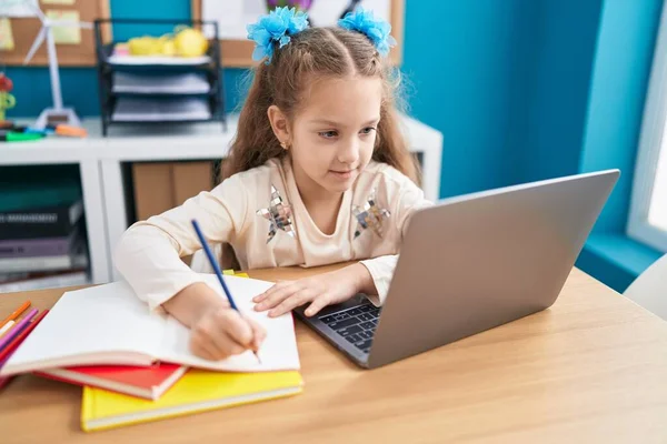 stock image Adorable caucasian girl student using laptop writing on notebook at office