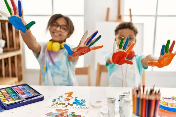 Brother and sister wearing headphones showing painted palm hands at art studio