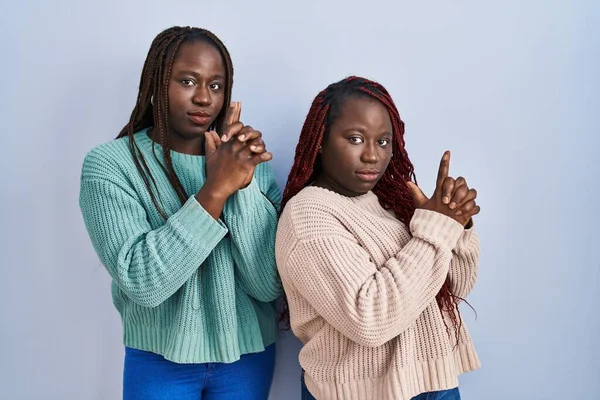 Две Африканки Стоящие Синем Фоне Держащие Руках Символический Пистолет Жестом — стоковое фото