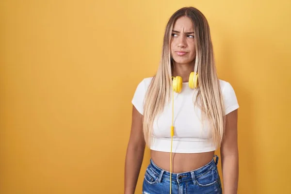 Young Blonde Woman Standing Yellow Background Wearing Headphones Smiling Looking — Zdjęcie stockowe
