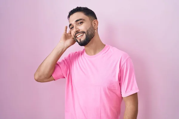 Іспанський Молодий Чоловік Стоїть Над Рожевим Фоном Усміхаючись Рукою Вухом — стокове фото