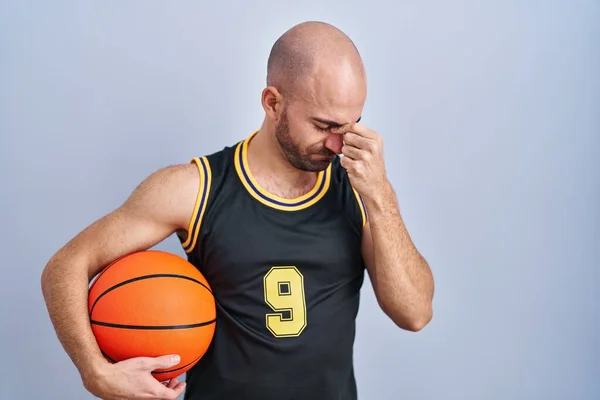 年轻的秃头男子 身穿篮球服 拿着球 疲惫地揉着鼻子和眼睛 感觉疲劳和头痛 压力和挫败感概念 — 图库照片